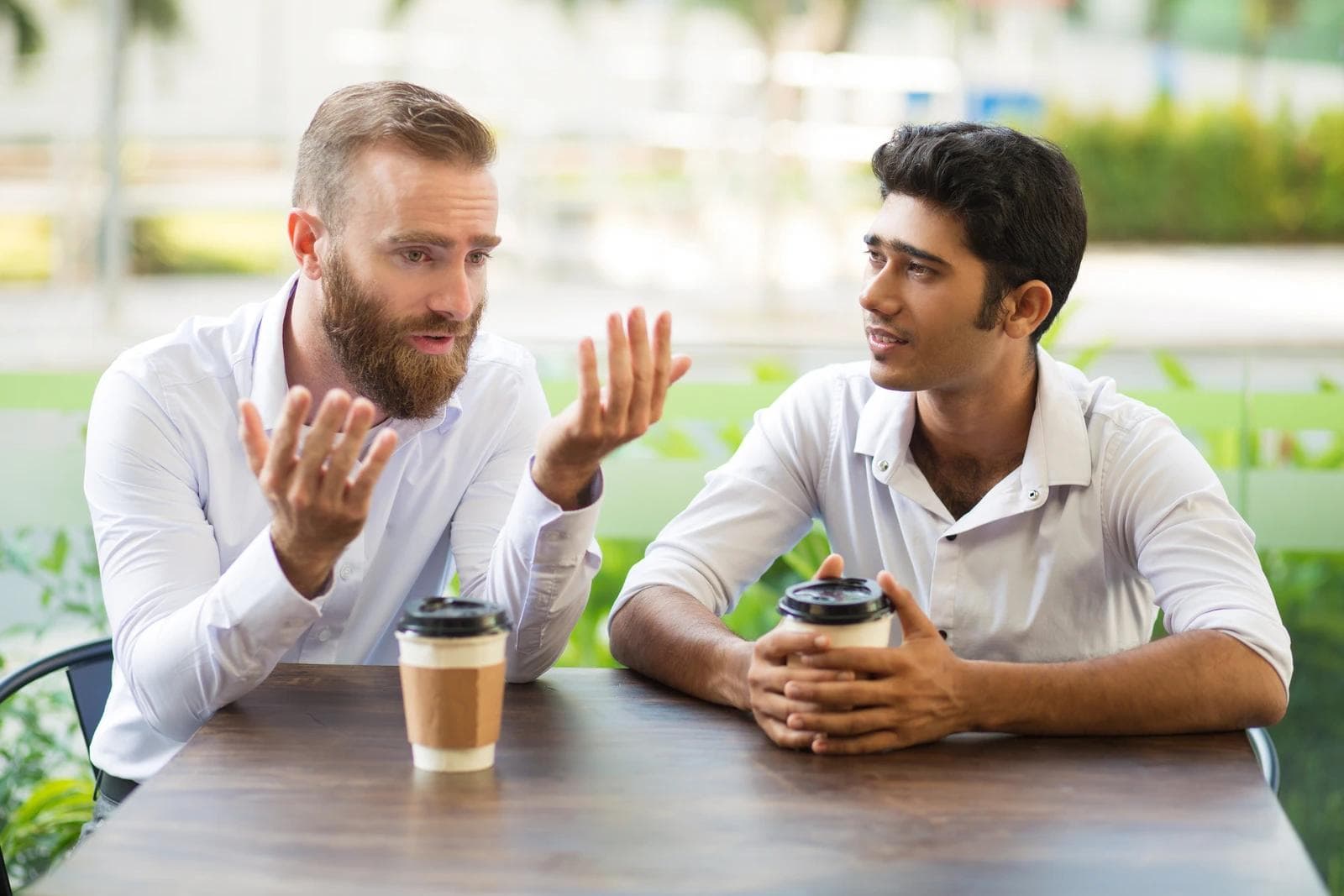 Two people seated across from each other at a café table in San Francisco, mid-conversation, one listening without rush.