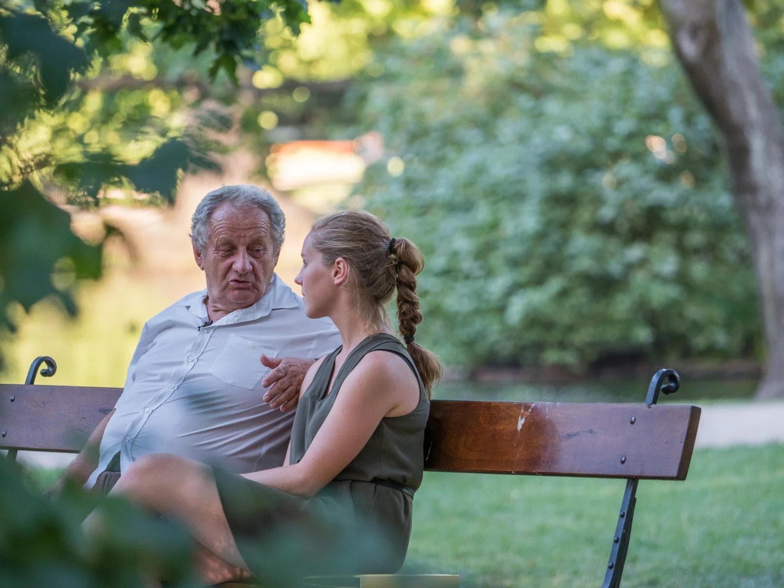 Two people sitting on a bench, listening to one another, intent on hearing each other