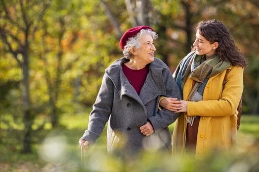 An older women and a younger woman walking together in the park have a deep meaningful experience